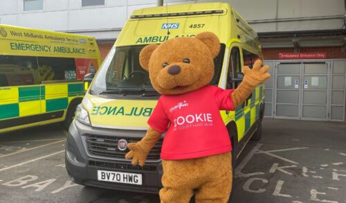 Cookie The Courtyard Bear standing in front of an ambulance