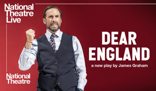 National Theatre Live Dear England Joseph Fiennes stands in a waistcoat against a red background He clenches his right fist in the air speaking passionately