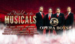 Four men stand in suits in front of an auditorium. Writing reads 'A Night At The Musicals Opera Boys'