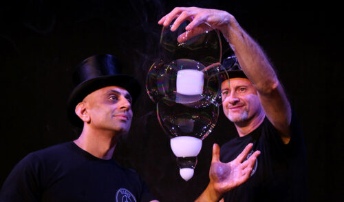 Two men in top hats looking at a large selection of bubbles