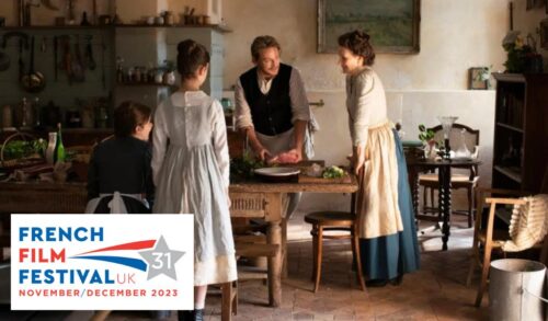 A man a woman and two children stand around a large wooden table covered in food