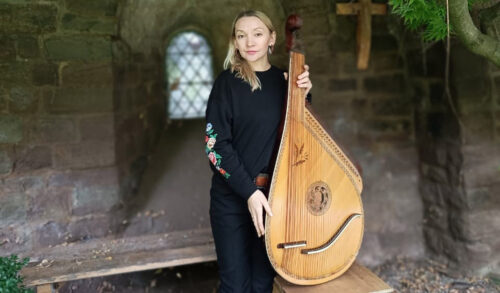 A woman stands with a large Ukrainian instrument