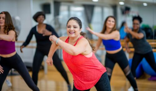 A group of women in gym gear smiling whilst dancing