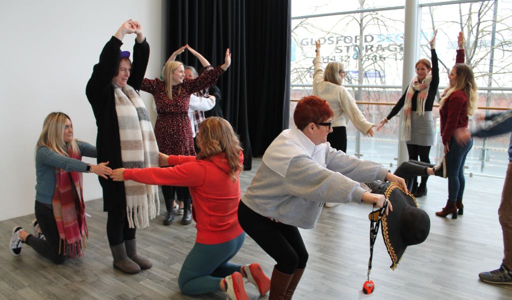 A group of adults pull different poses during a workshop