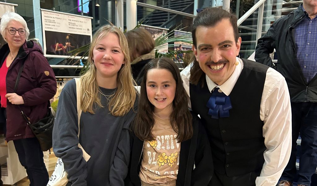Two young girls stand next to an actor smiling