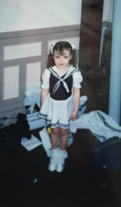 A young girl in a dress smiling at the camera