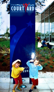 A young boy and young girl posing in front of The Courtyard sign