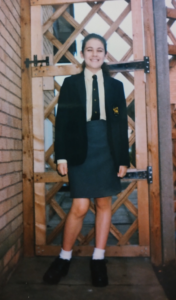 A young woman standing smiling in school uniform