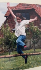 An image of a young girl jumping over a branch