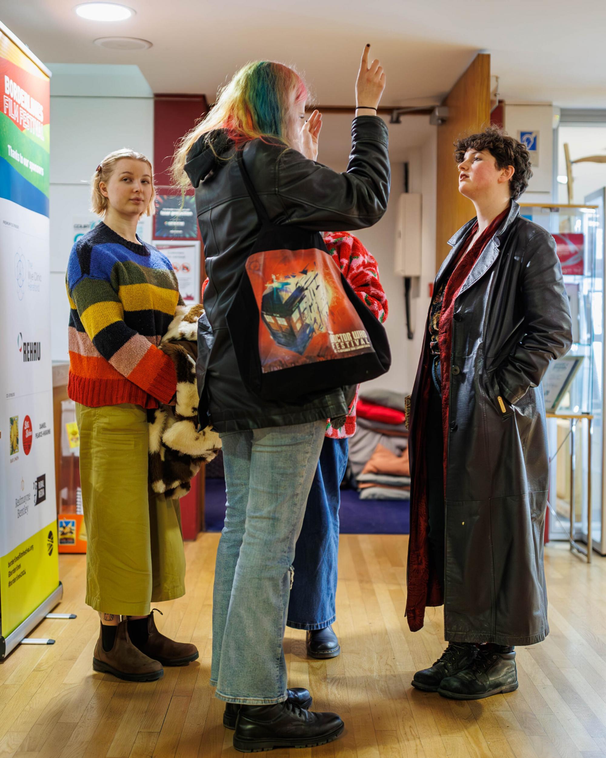 A group of cinema attendees stand around The Courtyard lobby chatting.