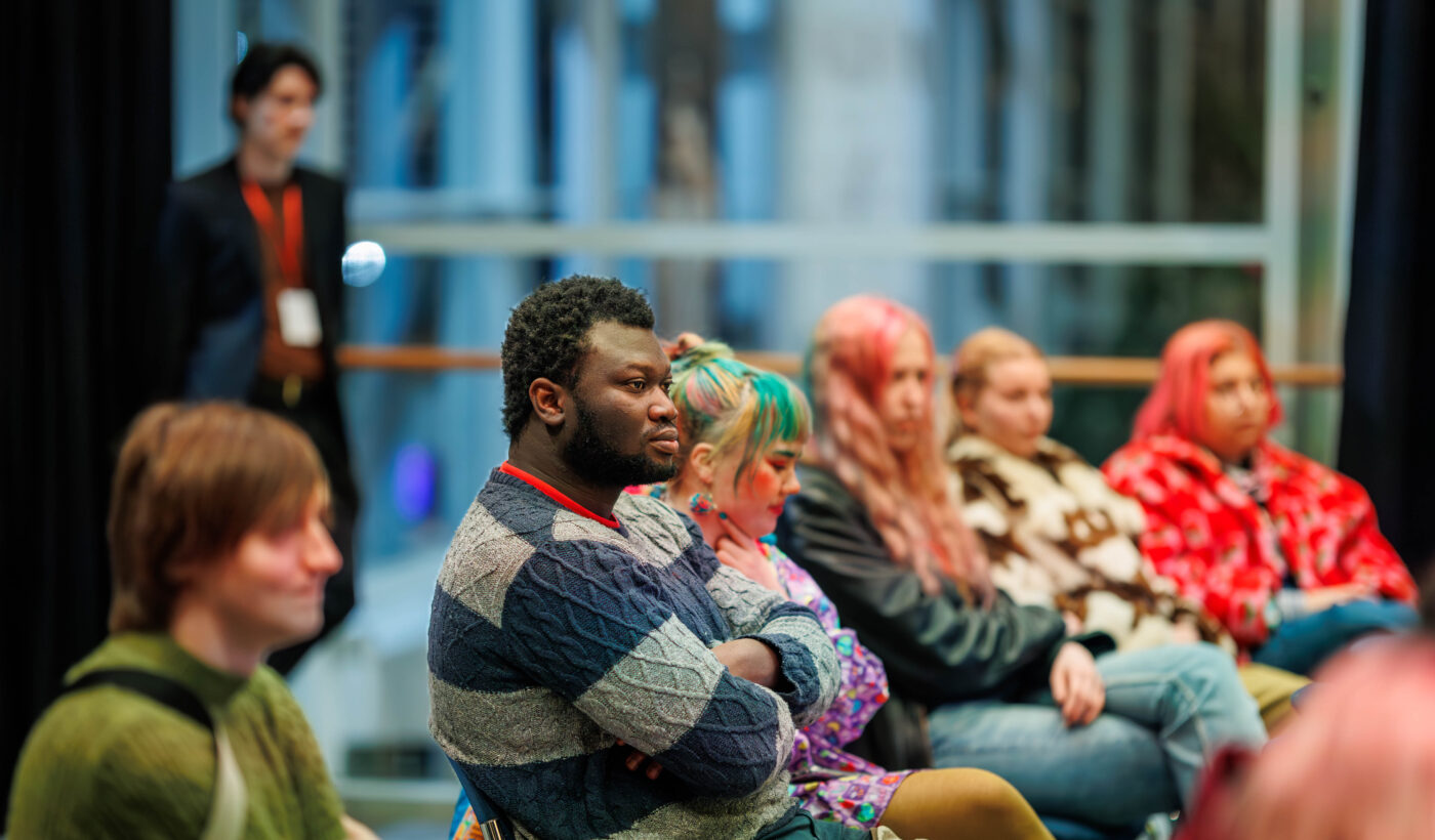 An audience in the Nell Gwynne sits looking toward the front. 