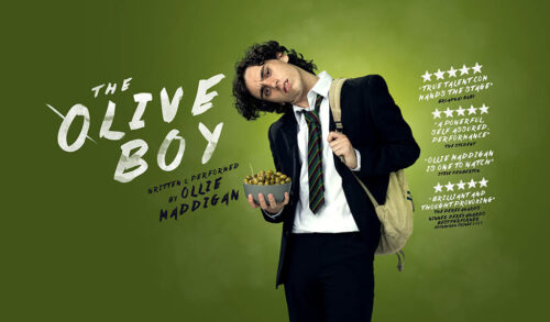 An image of a man wearing a suit and tie standing with his head on one side with a bag over his left shoulder holding a bowl of olives Writing reads The Olive Boy written and performed by Ollie Maddigan There are four reviews written down the right hand side