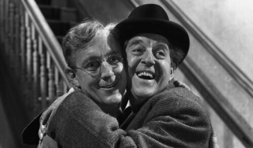 A black and white image of two men hugging one another with big smiles of their faces