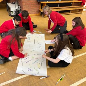 A group of children in school uniform drawing on a large piece of paper