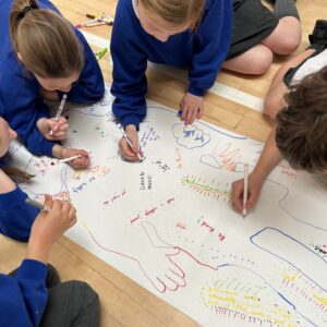 A group of school children drawing onto an outline of a person
