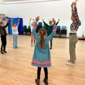 A young woman teaches a group of children in a drama workshop