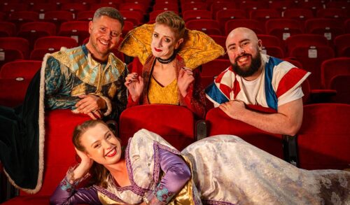 Four pantomime cast members in costume smiling in The Courtyard auditorium