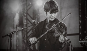 A black and white image of a young man playing the violin.