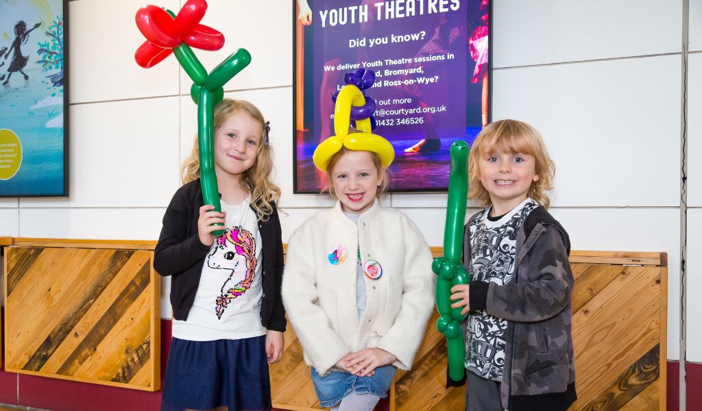 Three children pose with balloon animals