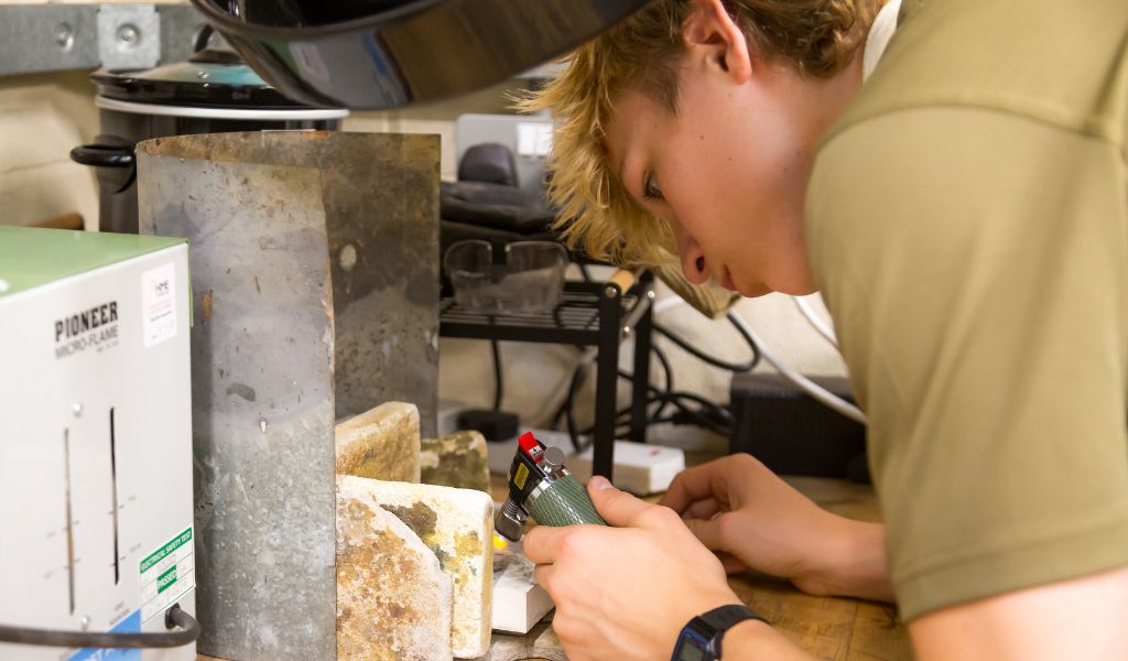 A young man solders a piece of jewellery