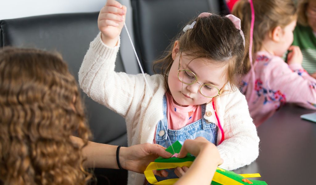 A young girl sews a piece of fabric