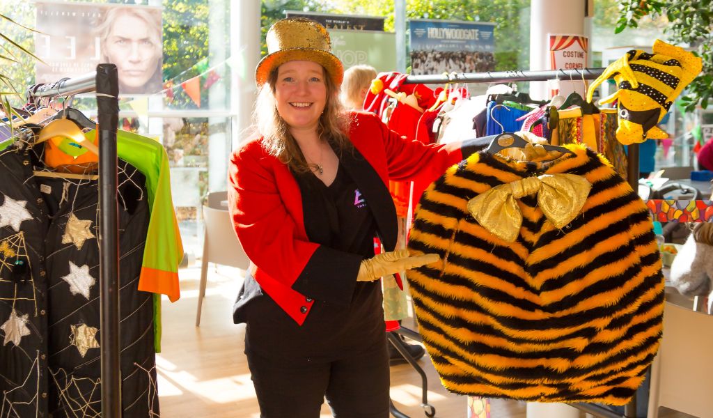 A woman dressed as a ringmaster holds a bee costume