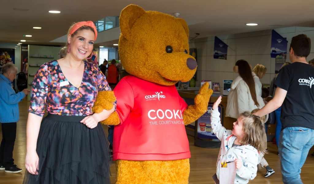 A little girl high fives The Courtyard's mascot, Cookie. 