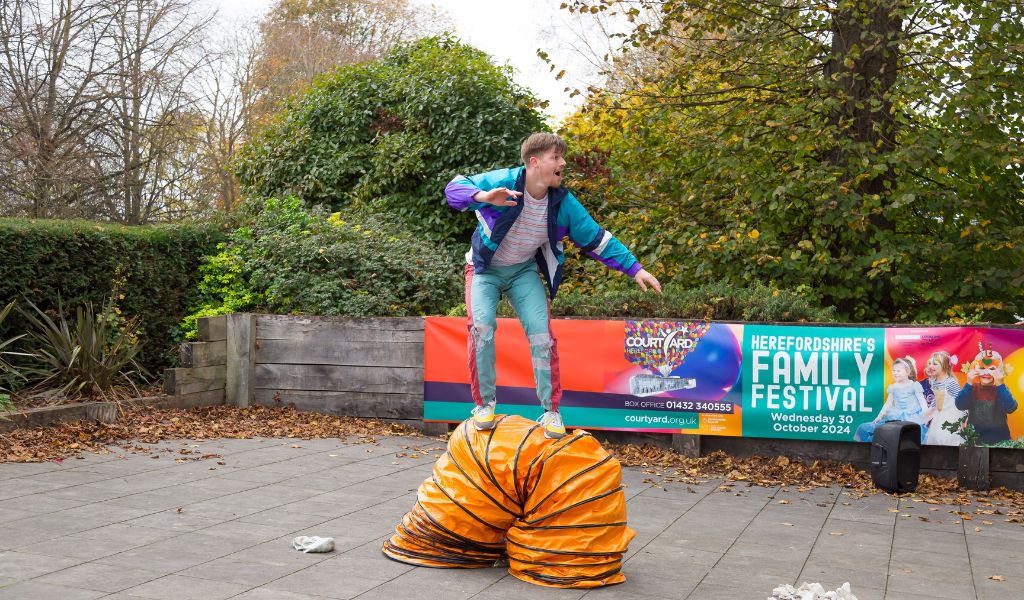 A man balances on a giant orange tube.