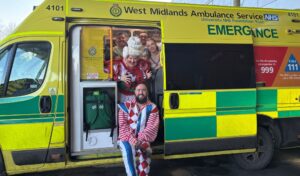 Five members of the pantomime cast in costume sitting in an ambulance