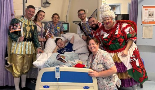 The cast of Sleeping Beauty in costume with a patient and member of staff in the childrens ward at Hereford Hospital