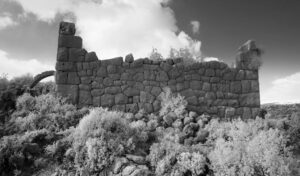 A black and white image of a wall in a desolate landscape.