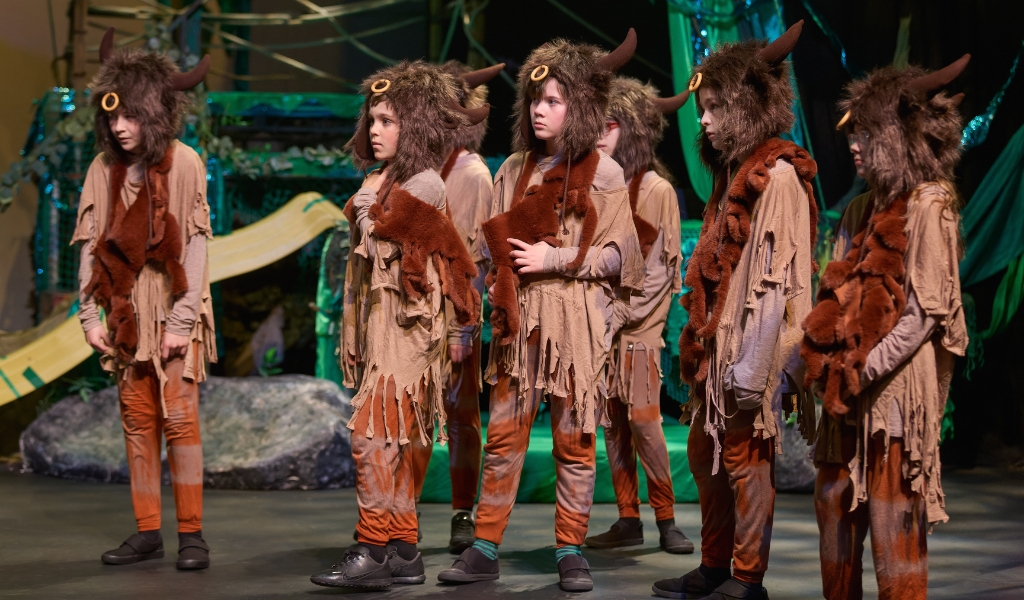 A group of children dressed as bisons on stage.