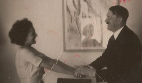 A black and white archival photo of a woman shaking the hand of Adolf Hitler