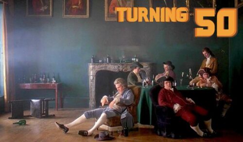 A still image from a period film featuring men in 18th century British clothing lounge in a stately home