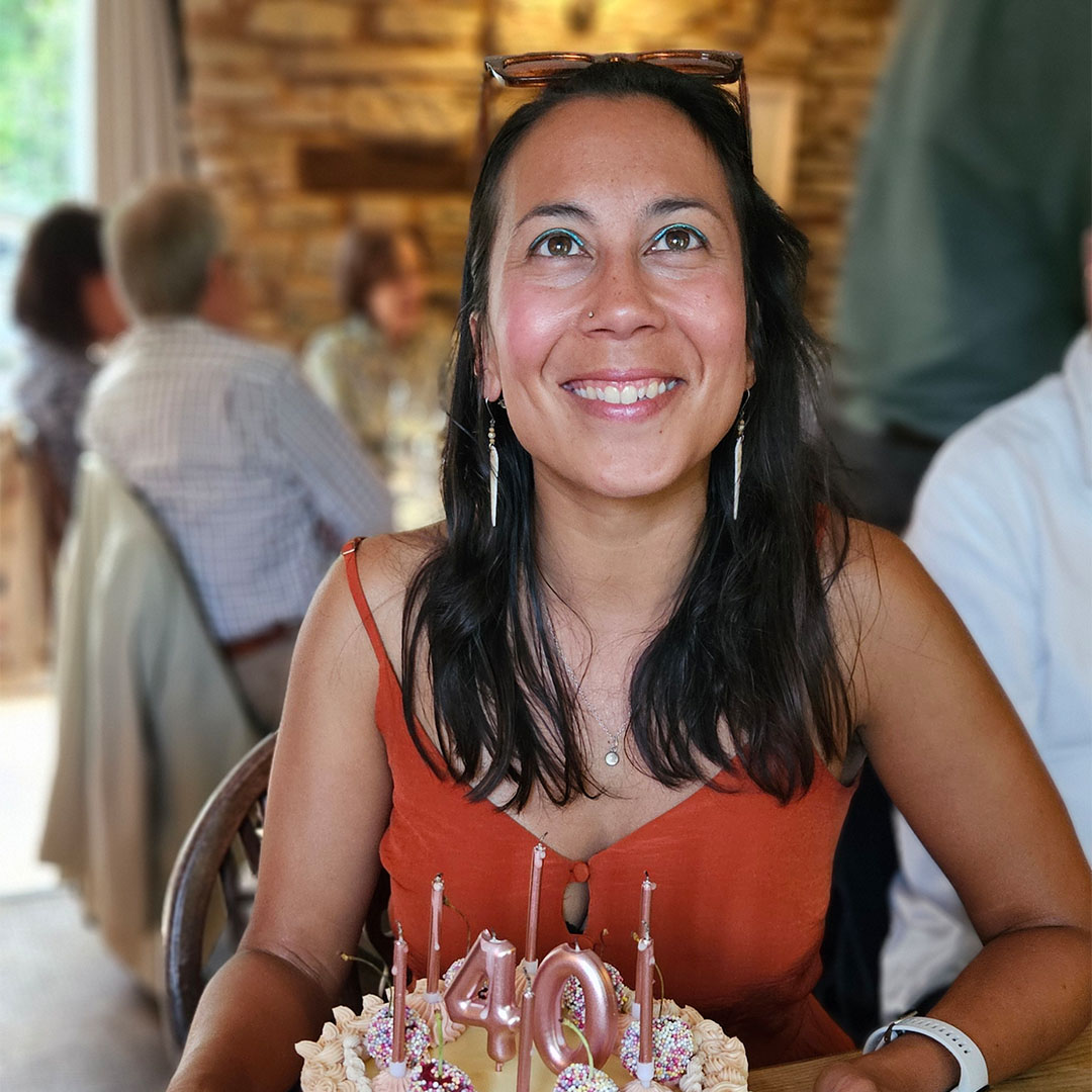 A woman in an orange top smiling at something above her.