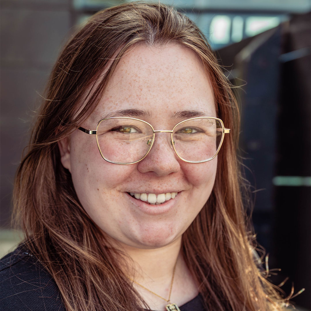 A woman wearing glasses smiling at the camera.