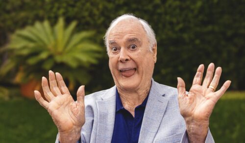 A photo of John Cleese sticking his tongue out and waving his hands in the air