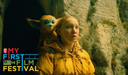 A girl in a yellow raincoat stands with a small monkeylike creature sat on her shoulder In the bottom left is the My First Film Festival logo