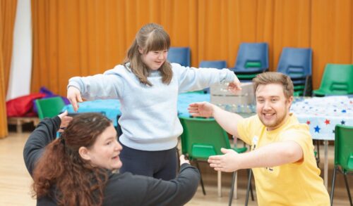 A man woman and girl stand in a circle with arms spread wide smiling