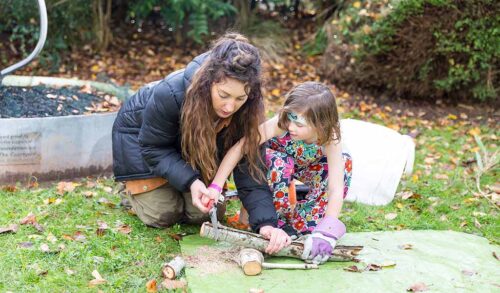 A woman and a child playing with sticks outside
