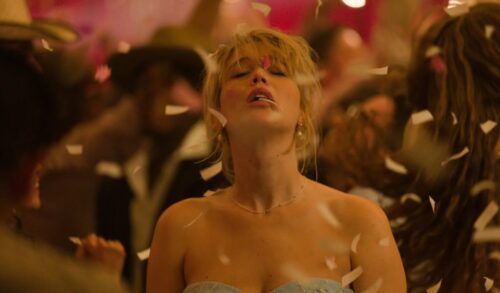 A woman stands with her head tilted back as confetti falls around her