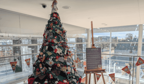 An image of a knitted tree with a sign next to it