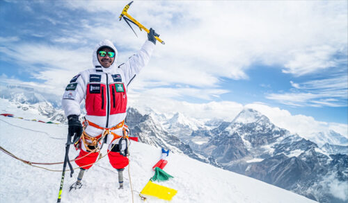 A man with two prosthetic legs standing on top of a mountain