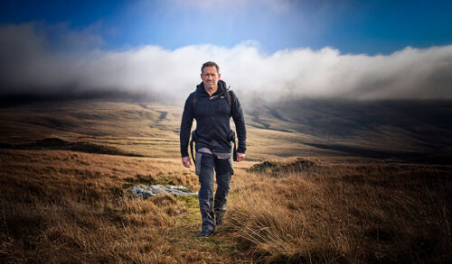 A man in walking gear walking in the hills