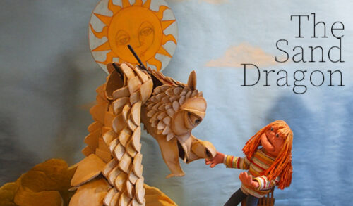 Two puppets  one of a dragon and one of a young girl with a cartoon sun above them The text in the top left corner reads The Sand Dragon