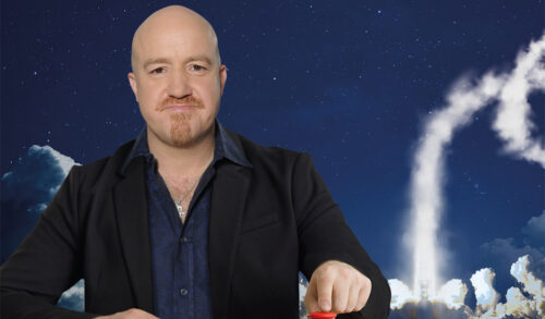 A bald man with a beard and a wry smile pushing a red button on a table with an image of a rocket going off in the background The text around him reads Andy Parsons  Please Eff Off To Mars