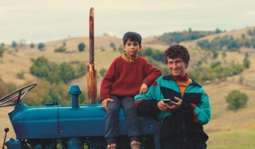A young boy and a man sit on a tractor