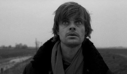 A blackandwhite image of a man in a winter coat with a concerned expression