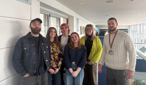 An image of 5 young people and an older man standing in front of a gallery